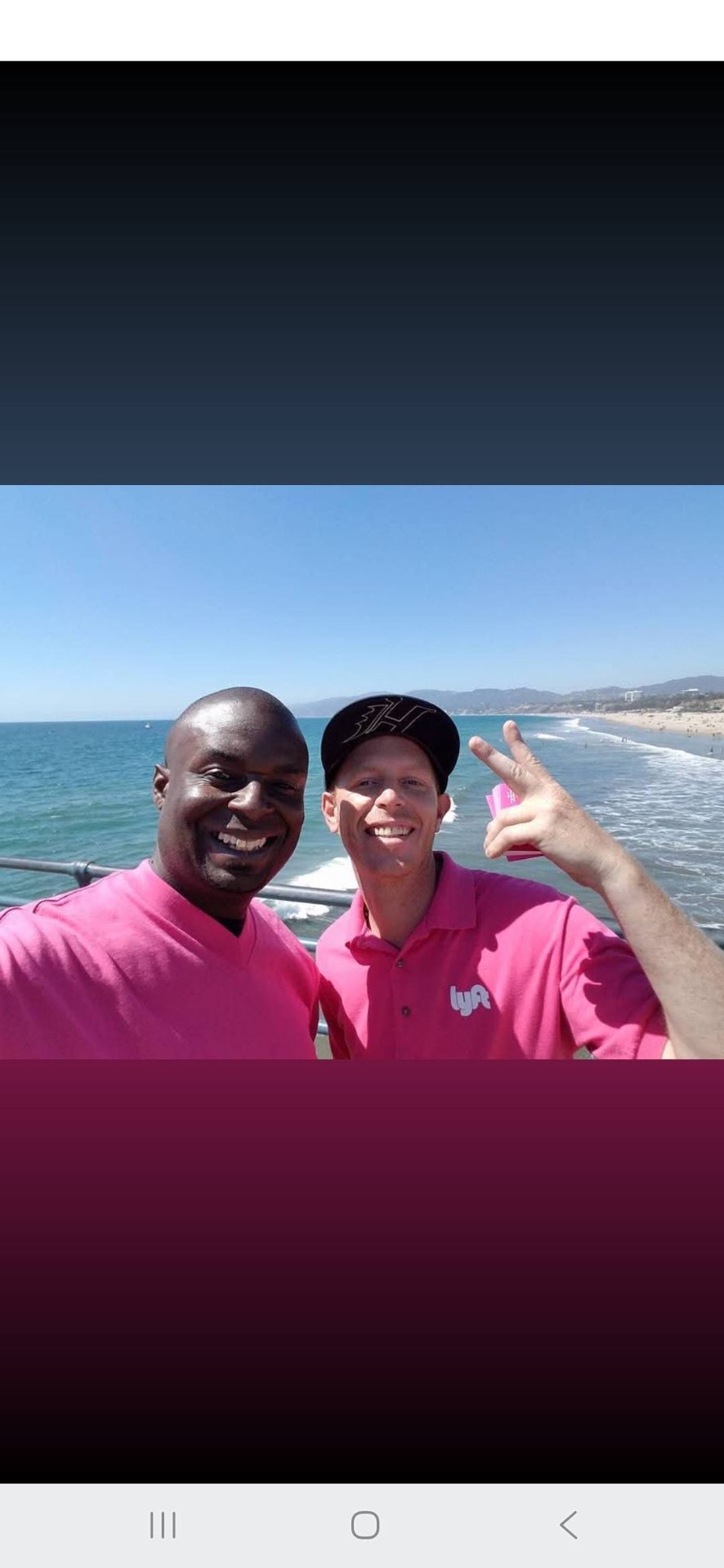 Two Lyft street team members in pink shirts on the Santa Monica Pier holding promo cards